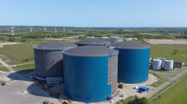 Four large cylindrical hot-water storage tanks at Aalborg’s district heating site in Denmark.