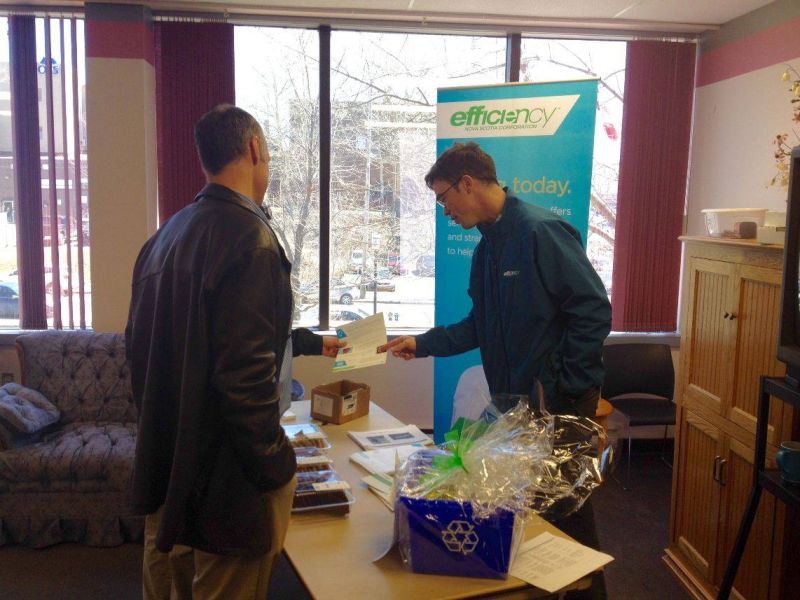 Two people talk beside an energy efficiency information table and Efficiency Nova Scotia banner.