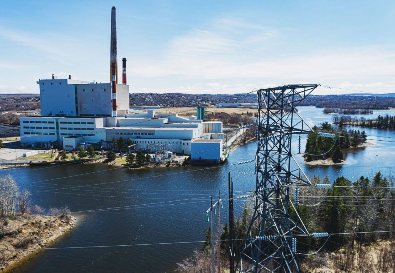 Electricity generation facility and transmission infrastructure beside a body of water.