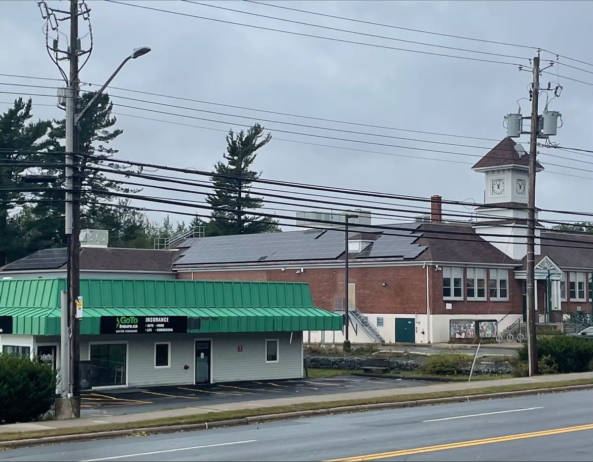 Rooftop solar panels on a brick community building with a clock tower.