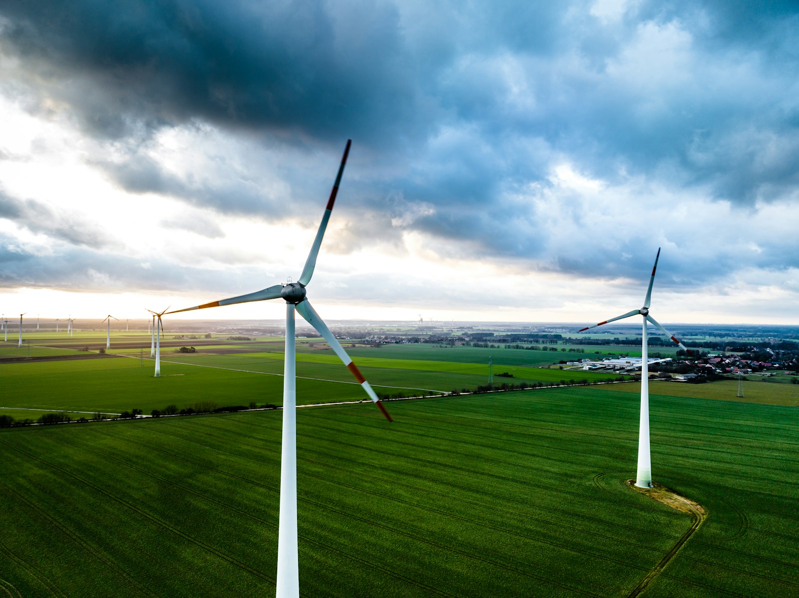 Wind turbines over green farmland beneath a cloudy sky in Brandenburg, Germany.