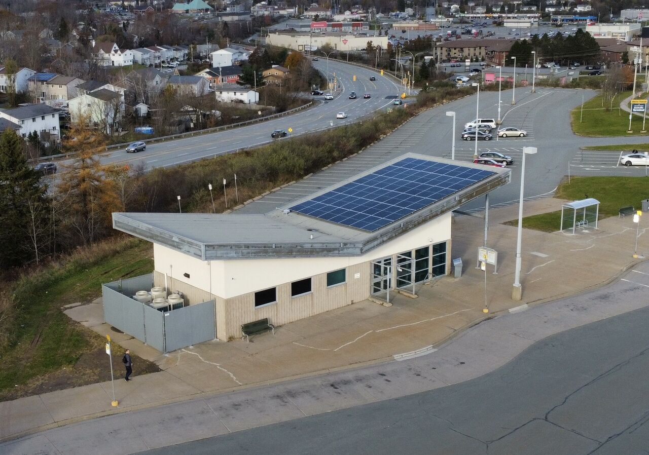 Aerial view of a transit terminal with rooftop solar panels and adjacent mechanical equipment.