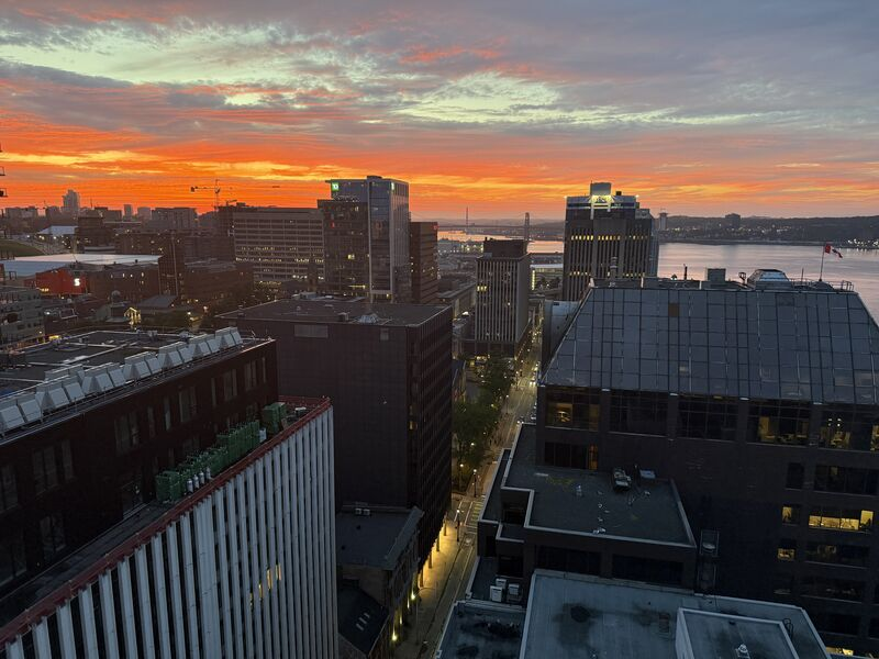 Downtown Halifax buildings and harbour beneath an orange sky.
