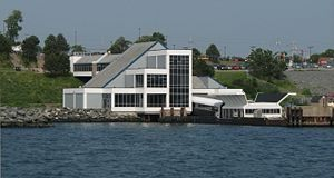 Waterfront building with an angular roof beside a shoreline.