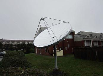 Dish-shaped solar apparatus mounted outdoors near buildings.