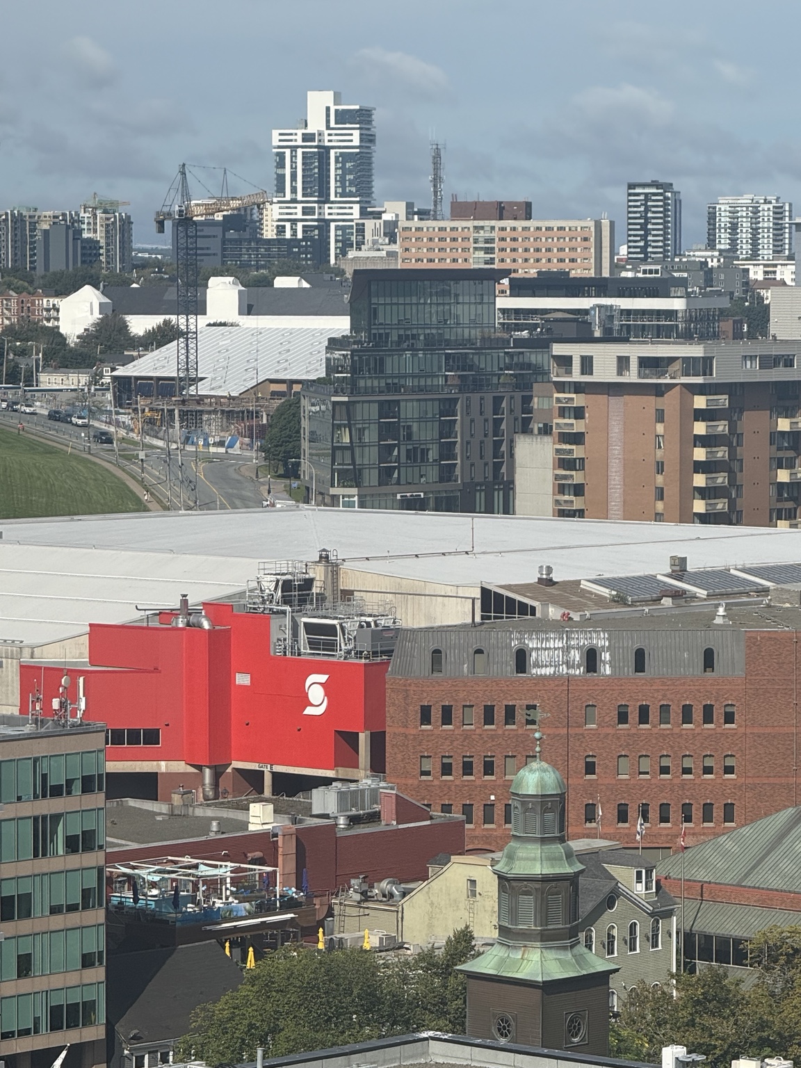 An elevated view of Scotiabank Centre, with its red entrance facade and rooftop equipment amid downtown Halifax buildings.